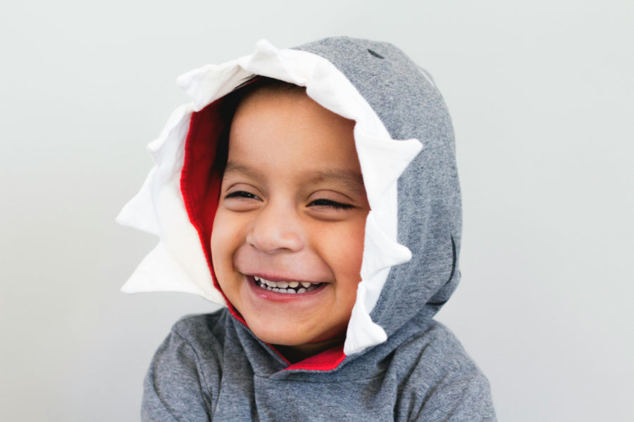 Close-up of smiling toddler in a shark hoodie showing healthy baby teeth, highlighting why baby teeth are important for confidence and joyful smiles.